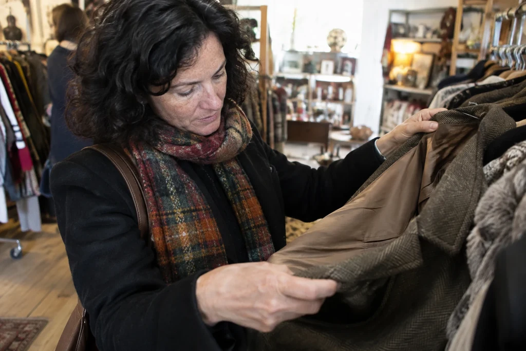 Des mains écartent doucement une doublure de manteau pour regarder son état.