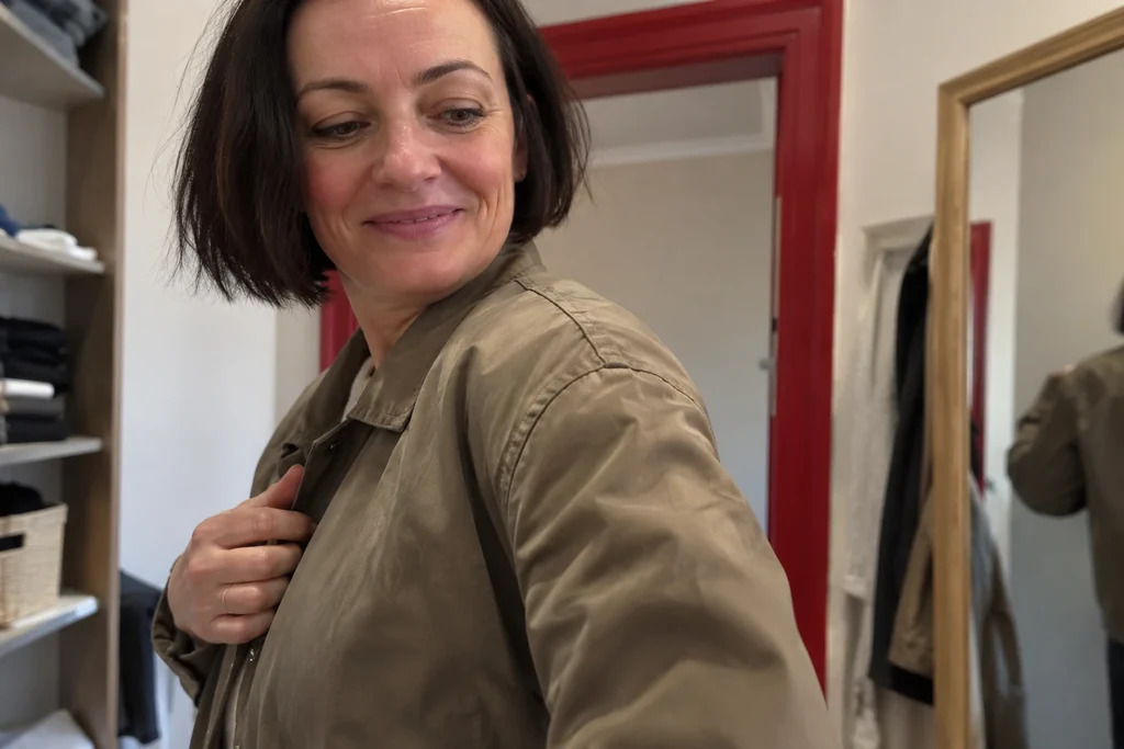 Le détail d’une épaule et d’une manche de veste portées est visible en lumière naturelle.