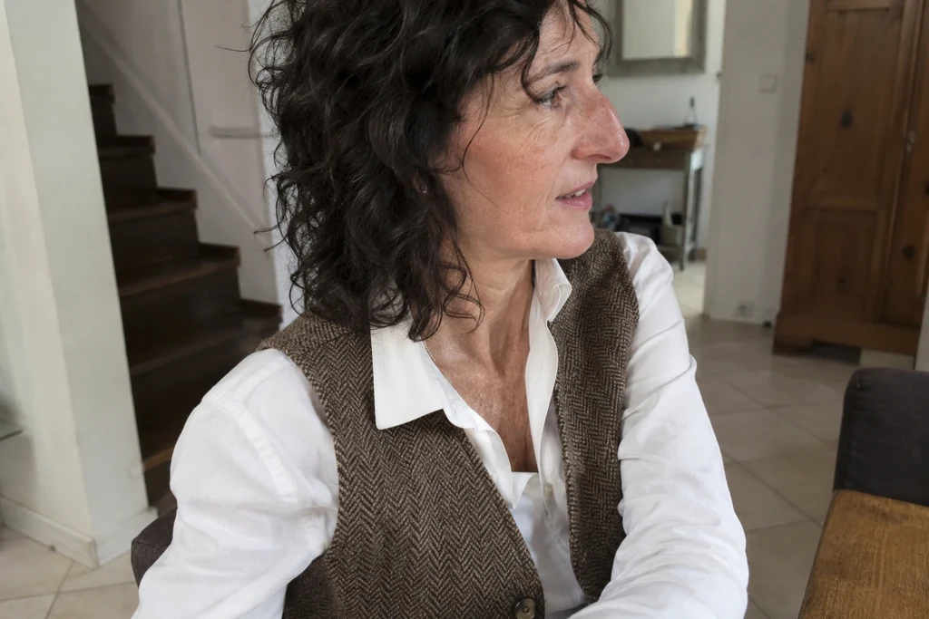 Le bord d’une emmanchure de gilet est visible sur une chemise portée.