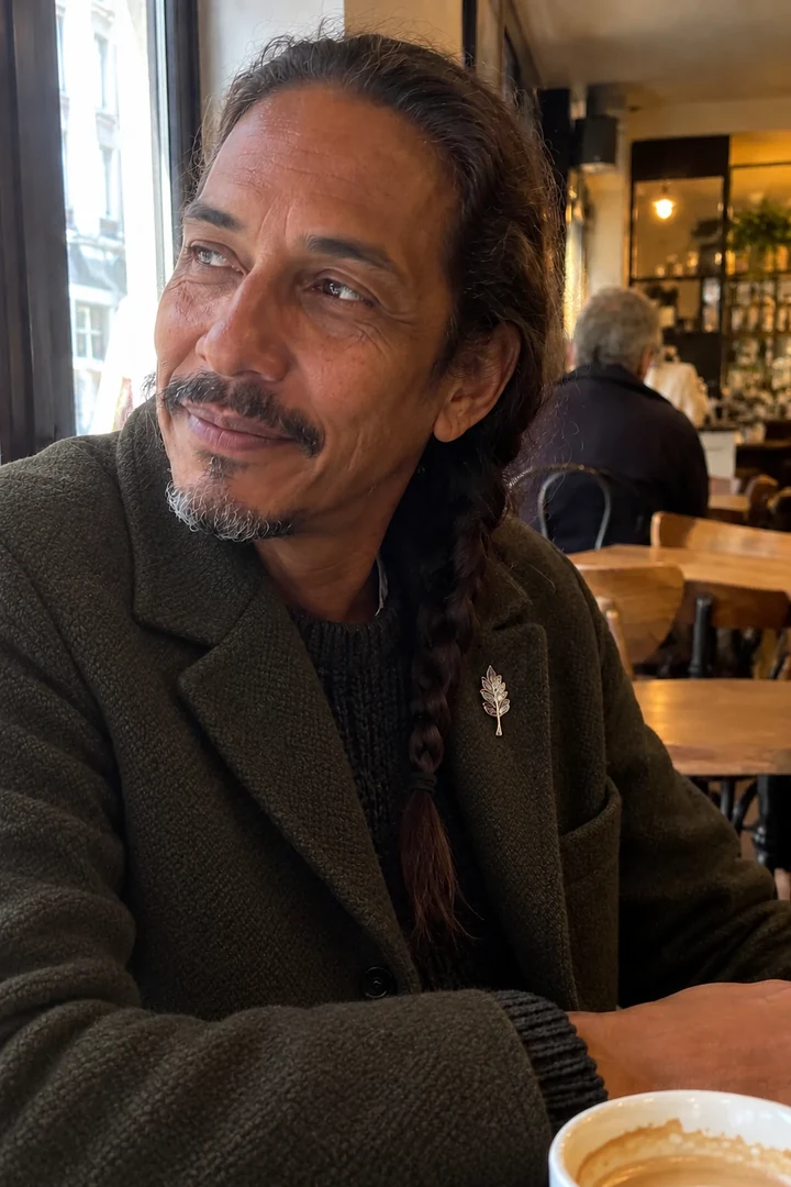 Un homme porte une broche discrète sur le revers d’une veste dans un café.