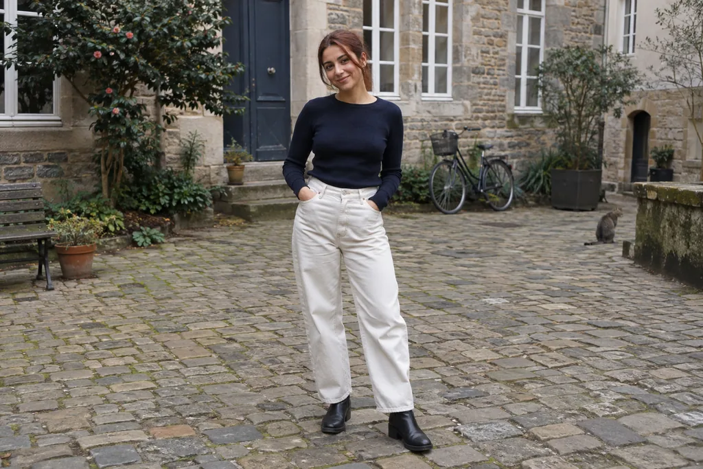 Un jean barrel écru est associé à un haut marine et à des bottines.