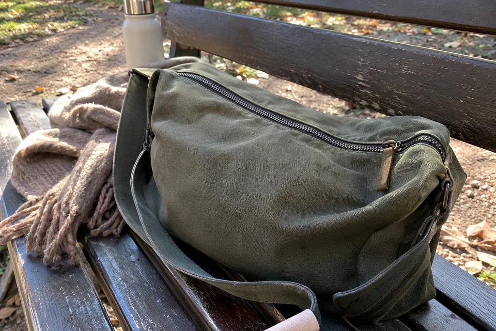 La fermeture zippée d’un sac souple est visible sur un banc.