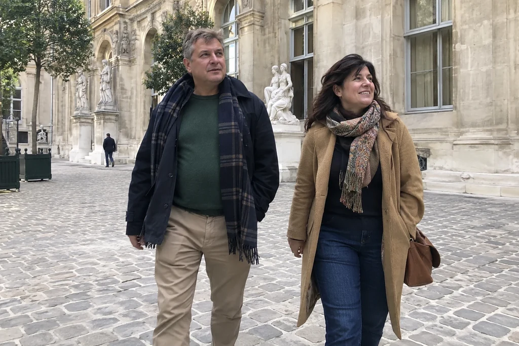Deux amis adultes marchent dans une cour de musée avec des tenues quotidiennes pratiques.