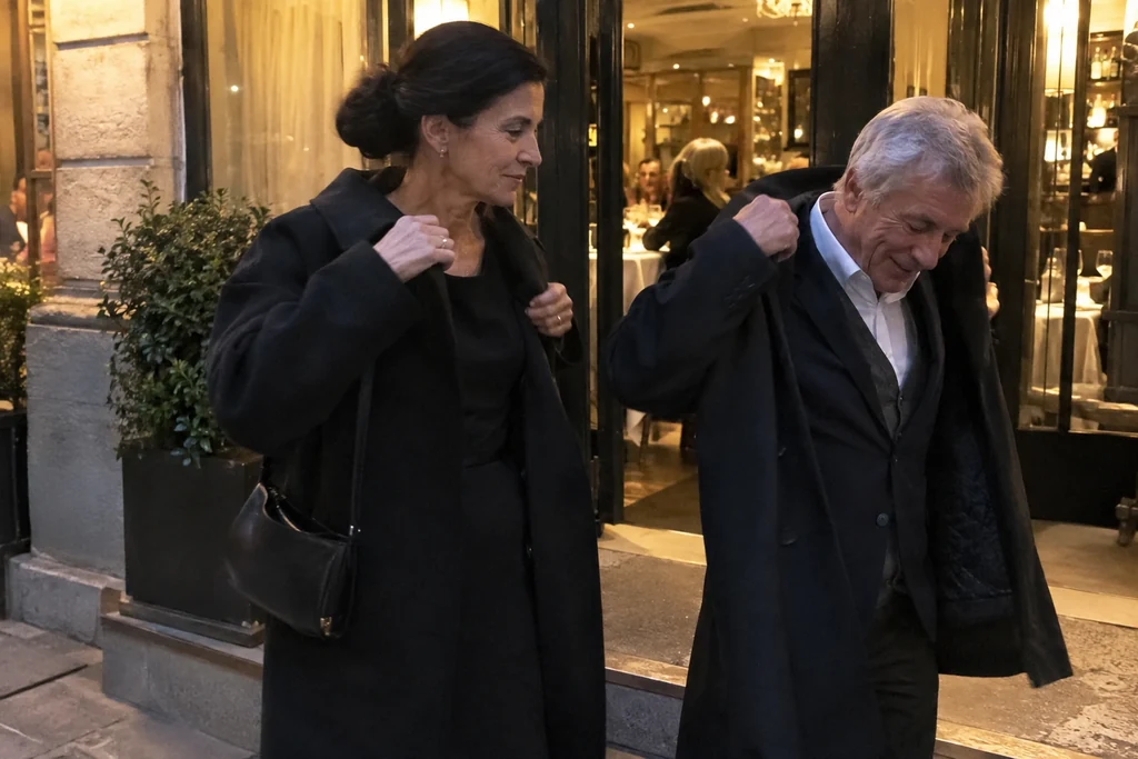 Deux adultes en tenues soignées et simples remettent leurs manteaux devant un restaurant après le dîner.