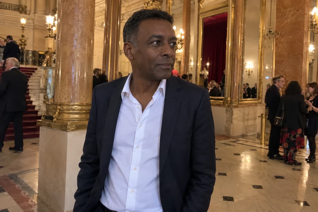 Un homme en chemise à col ouvert et veste attend dans un foyer de théâtre.
